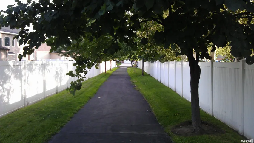 Paved pathway bordered by manicured lawn and privacy fencing