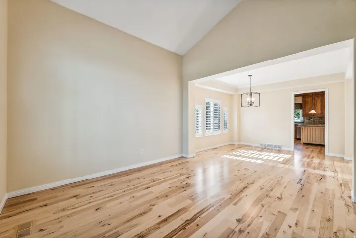 Vaulted ceiling, wood-finish flooring, plantation shutters, coffered ceiling, and a contemporary chandelier