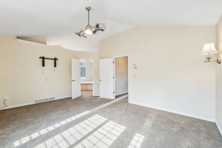 Vaulted ceilings, contemporary ceiling fan, wall-mounted light fixture, carpeted flooring, and white paneled doors