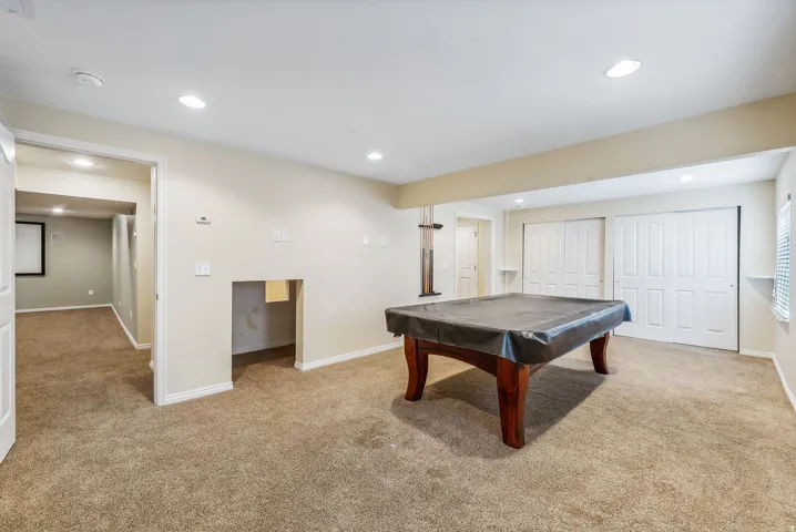 Recessed lighting, neutral-toned walls, and carpeted flooring