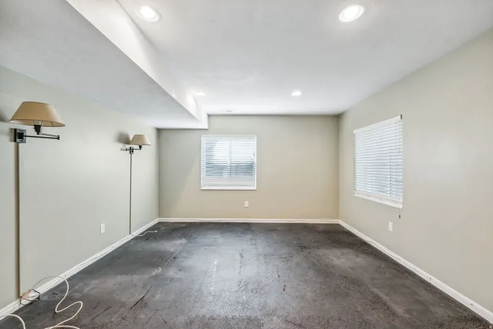 Recessed ceiling lighting illuminates the interior, featuring two windows with horizontal blinds and light-toned walls