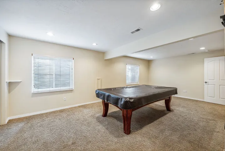 Spacious room featuring neutral carpeting, recessed lighting, and two windows with blinds