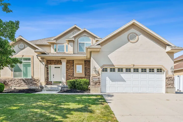 Stucco exterior featuring stone accents, a covered entry, multiple gables, and a two-car garage with paneling