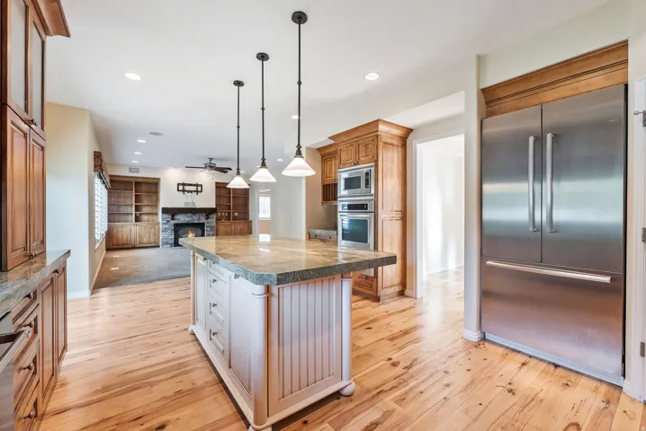 Kitchen featuring a central island with a stone countertop, recessed lighting, and wood-finish flooring