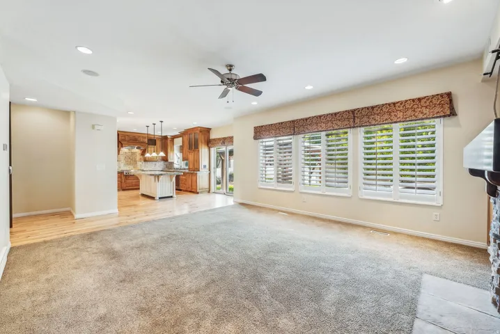 Recessed lighting, ceiling fan, plantation shutters, wood-finish flooring, and a stone-clad fireplace