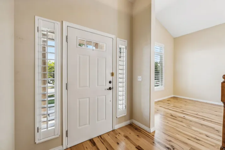 White paneled front door with decorative lites and flanking sidelites