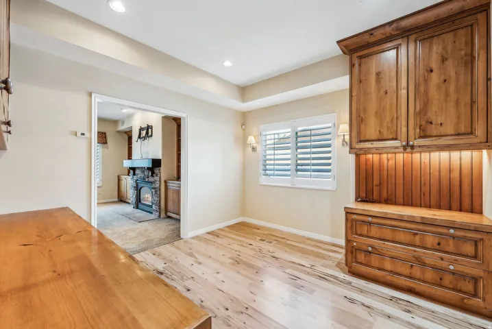 Wood-finish flooring, built-in wooden cabinetry with under-cabinet lighting, window with white plantation shutters, and recessed lighting