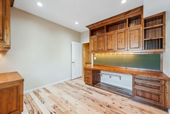 Built-in wood cabinetry, integrated desk space, recessed ceiling lighting, under-cabinet lighting, and wood-finish flooring