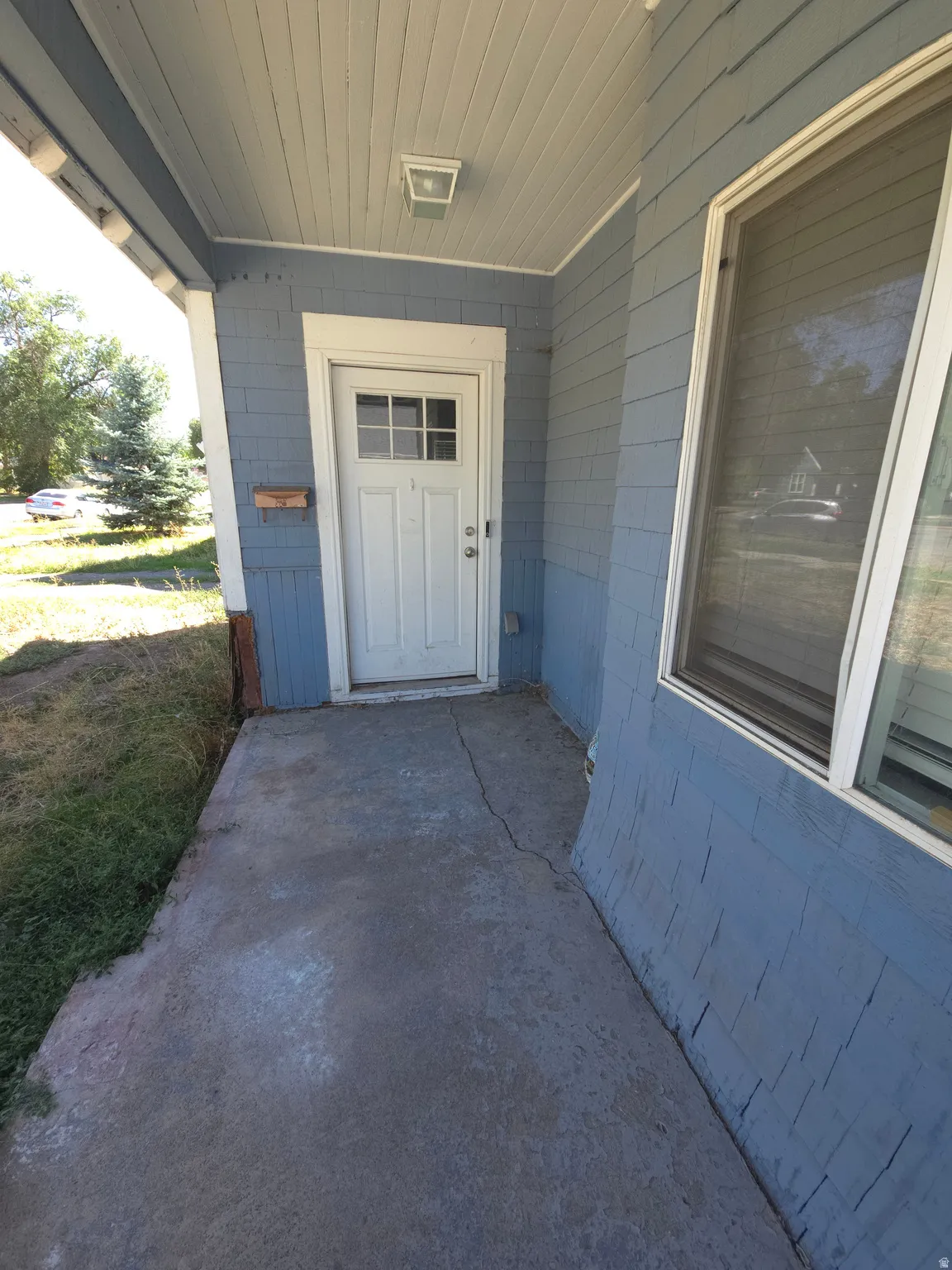 Covered front porch with concrete flooring and shingle siding