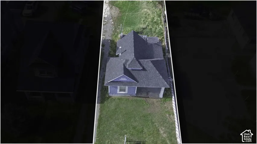 Aerial perspective of a detached residential structure featuring a multi-gable shingle roof, exterior siding, and a fenced perimeter