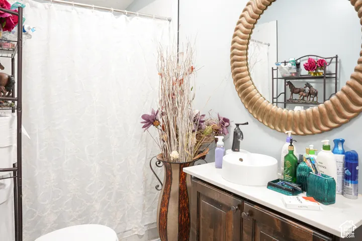 Vanity featuring a vessel sink, dark wood-finish cabinetry, and a circular mirror