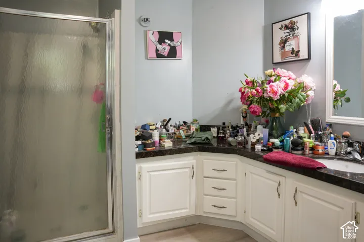 Shower with a framed glass door, light-colored walls, and a vanity with white cabinetry
