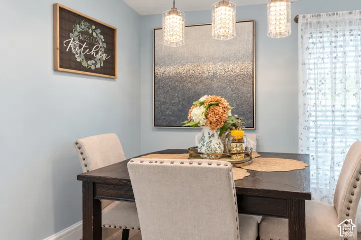 Wood-finish dining table with upholstered chairs featuring decorative nailhead trim