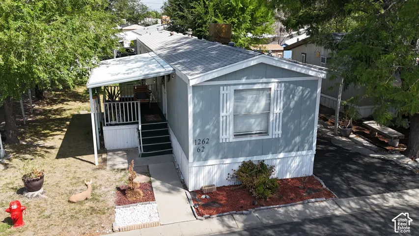 Light gray exterior with white trim, covered front porch with steps, white shutters, and a decorative front yard planter