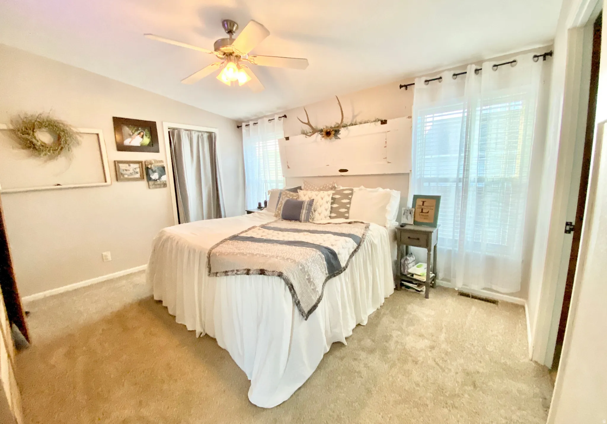 Vaulted ceiling with a ceiling fan, dual windows with blinds, carpet flooring, and neutral wall paint