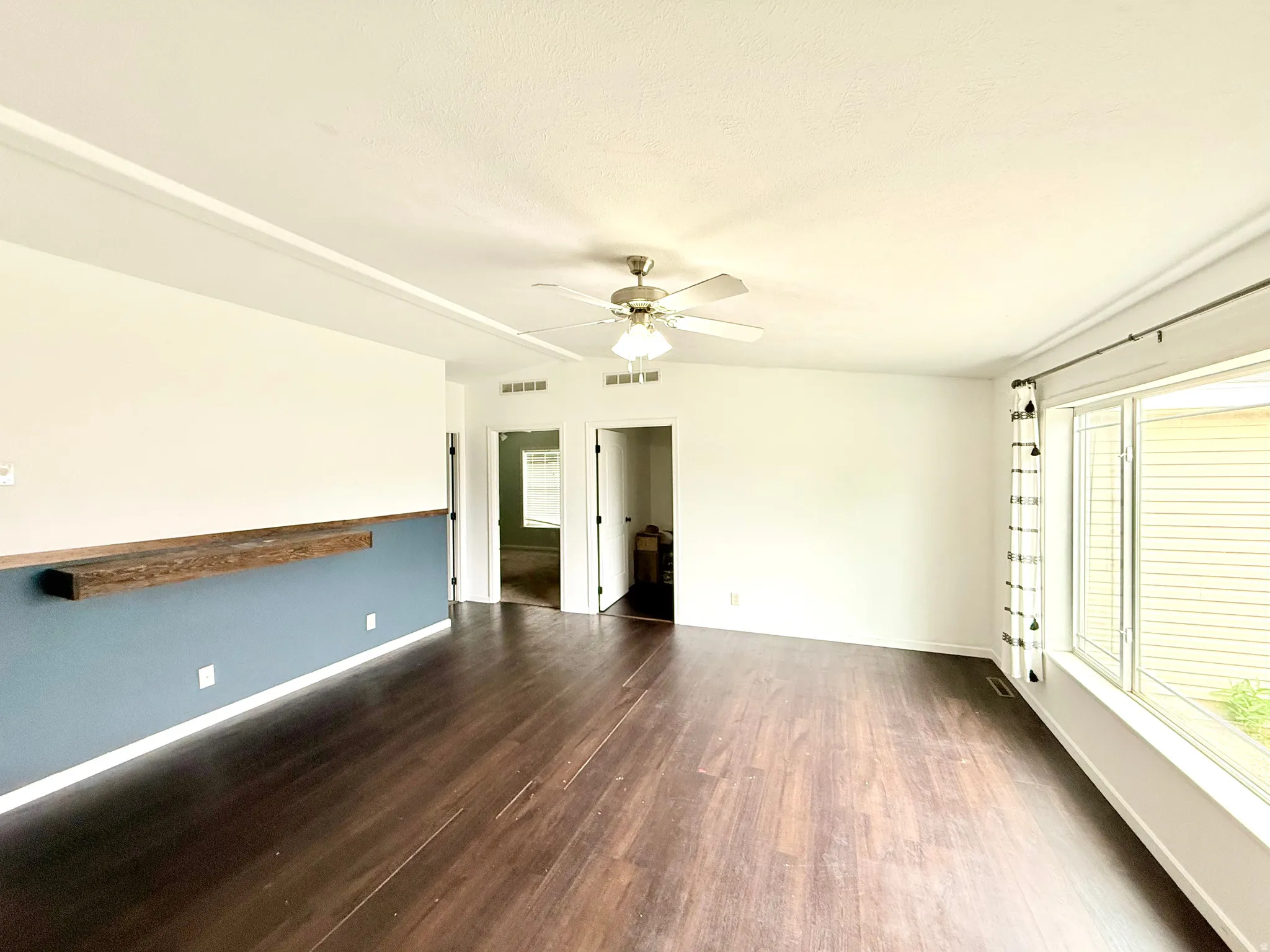 Wood-finish flooring, built-in wooden shelf, ceiling fan, and large windows