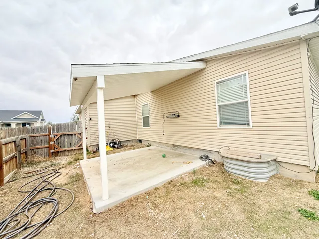 Covered patio with a concrete slab, vinyl siding, and white window blinds
