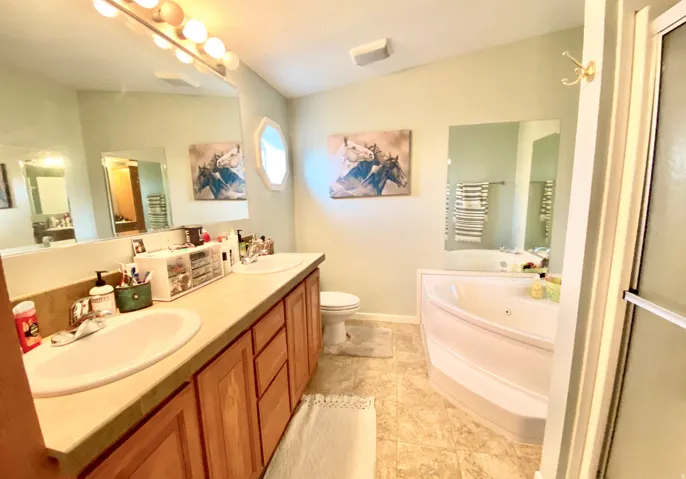 Double vanity with undermount sinks, warm wood-finish cabinetry, and an integrated countertop