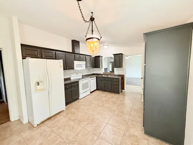 Kitchen featuring dark-finish cabinetry, tile flooring, and white appliances