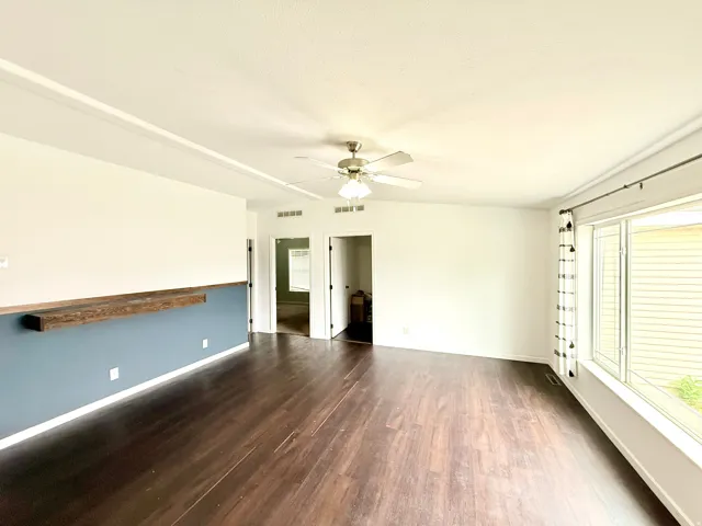 Wood-finish flooring, built-in wooden shelf, ceiling fan, and large windows