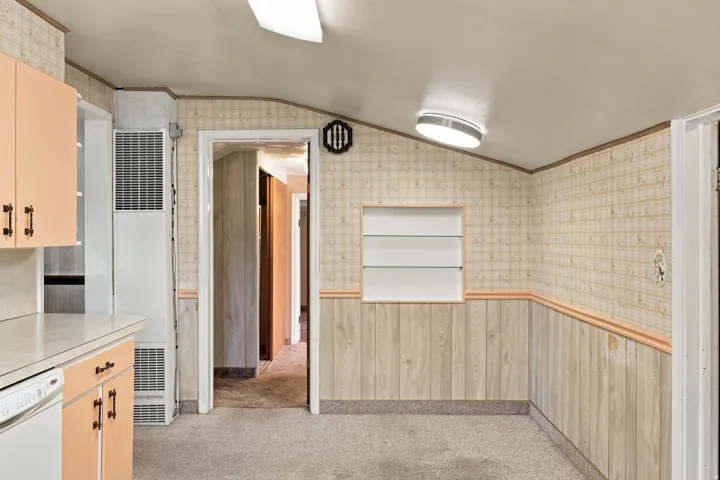 Built-in display niche with glass shelving, patterned wallpaper, wood-finish wainscoting, and carpeted flooring