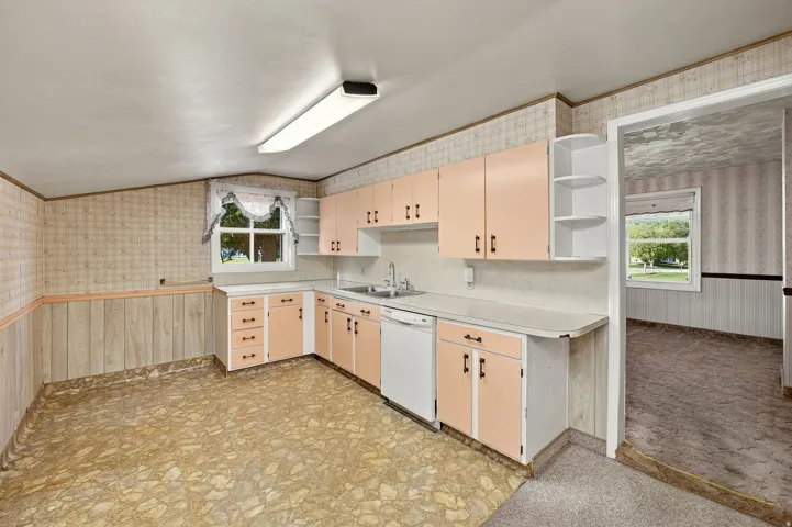 L-shaped cabinetry with upper and lower storage, integrated sink, and built-in dishwasher