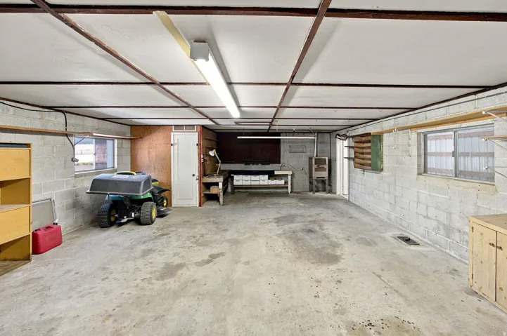 Spacious multi-purpose room with concrete block walls, concrete flooring, and built-in shelving