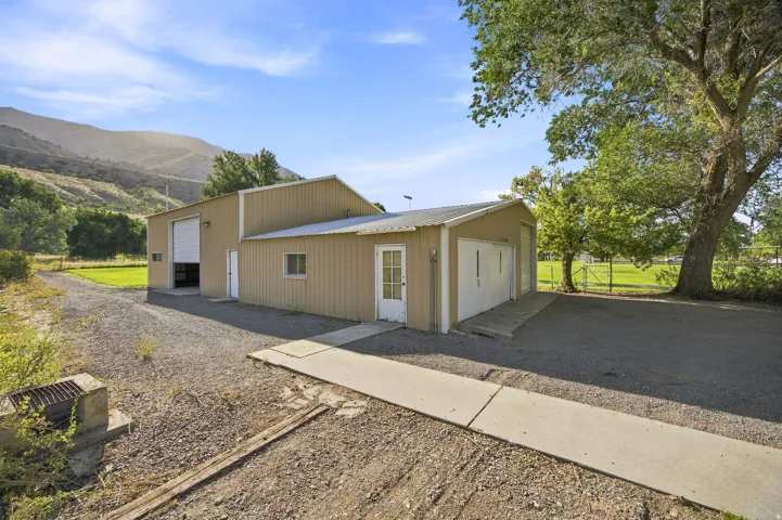 Metal-sided structure featuring multiple garage doors and a pedestrian entrance, set against a mountain backdrop