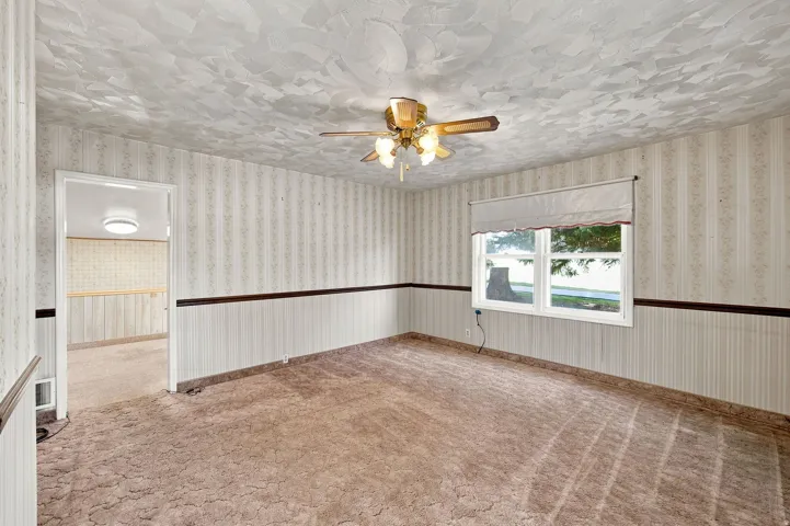 Window with exterior scenery, ceiling fan with light fixture, and textured ceiling