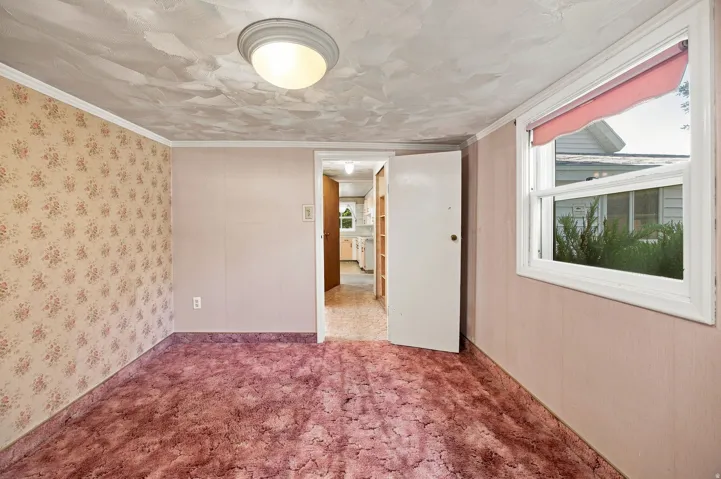 Recessed ceiling light fixture, window with white trim, wall-to-wall carpeting, and an interior door