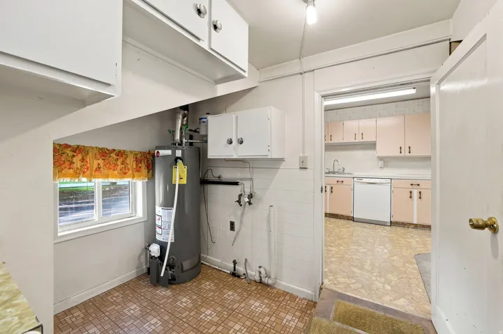 Utility area with patterned flooring and white cabinetry