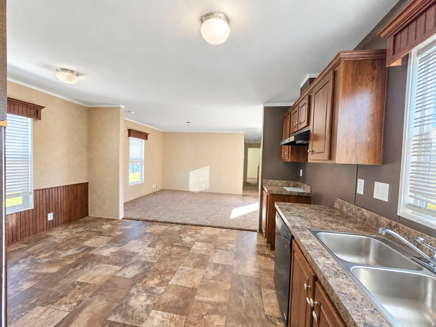 Kitchen featuring wood-finish cabinetry, a double basin stainless steel sink, and laminate countertops