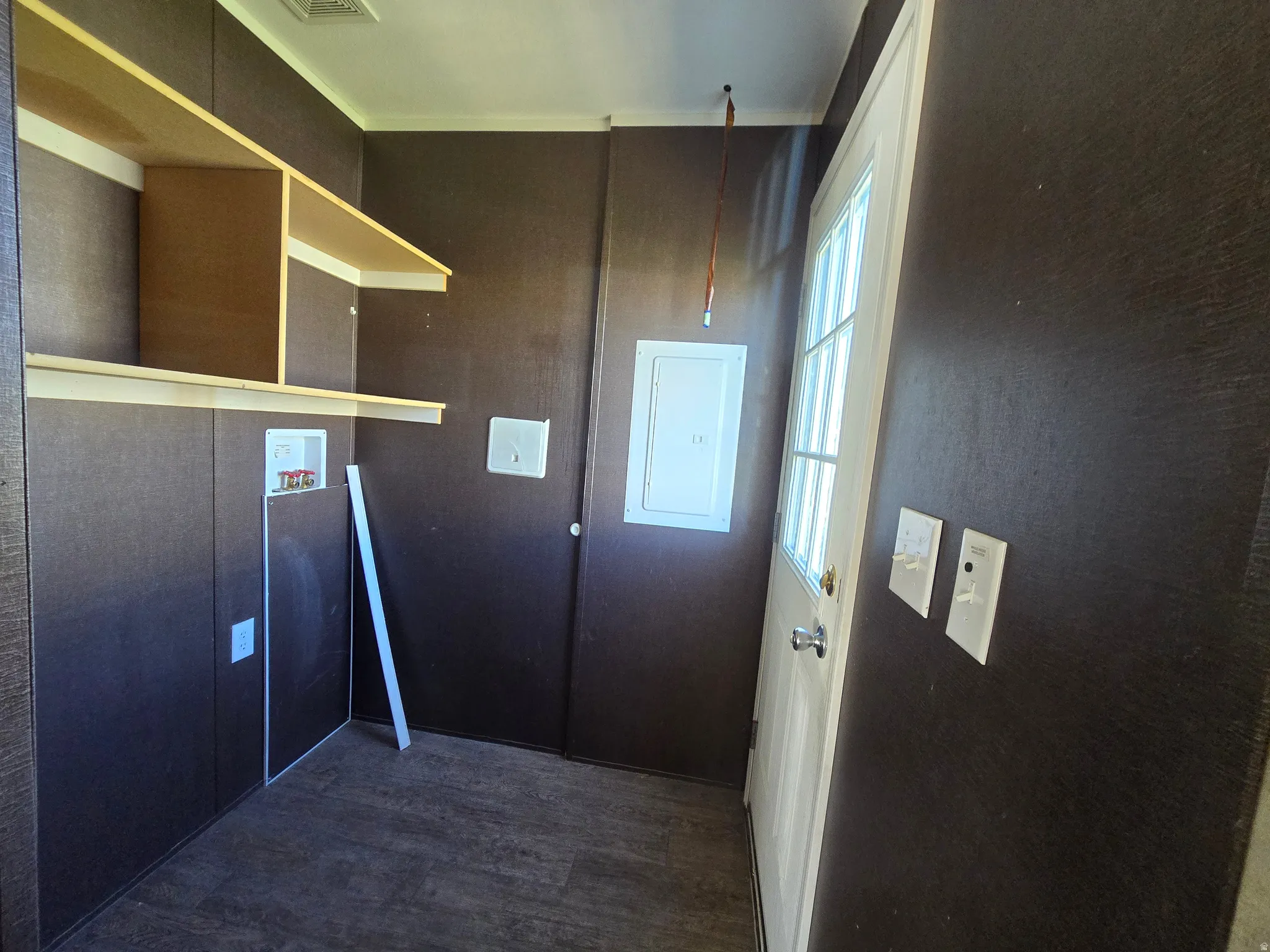 Utility space featuring wood-finish wall panels, built-in shelving, and a paneled exterior door