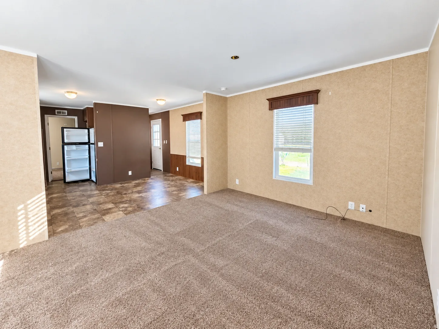 Spacious living area with neutral carpet flooring, a window with blinds, and recessed lighting