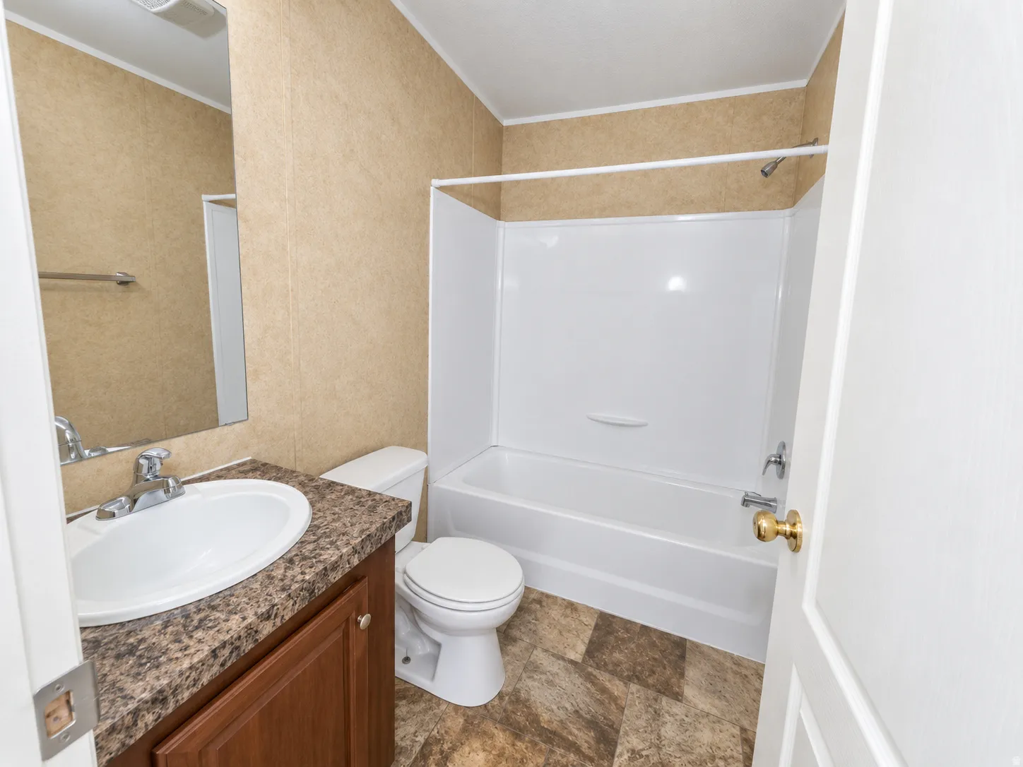 Bathroom featuring a white bathtub, a toilet, a vanity with a white basin sink, and a wall-mounted mirror