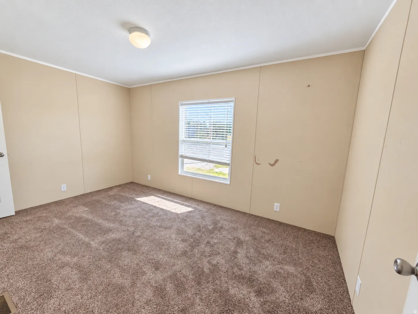 Carpeted flooring, single window with blinds, overhead lighting fixture, and paneled walls