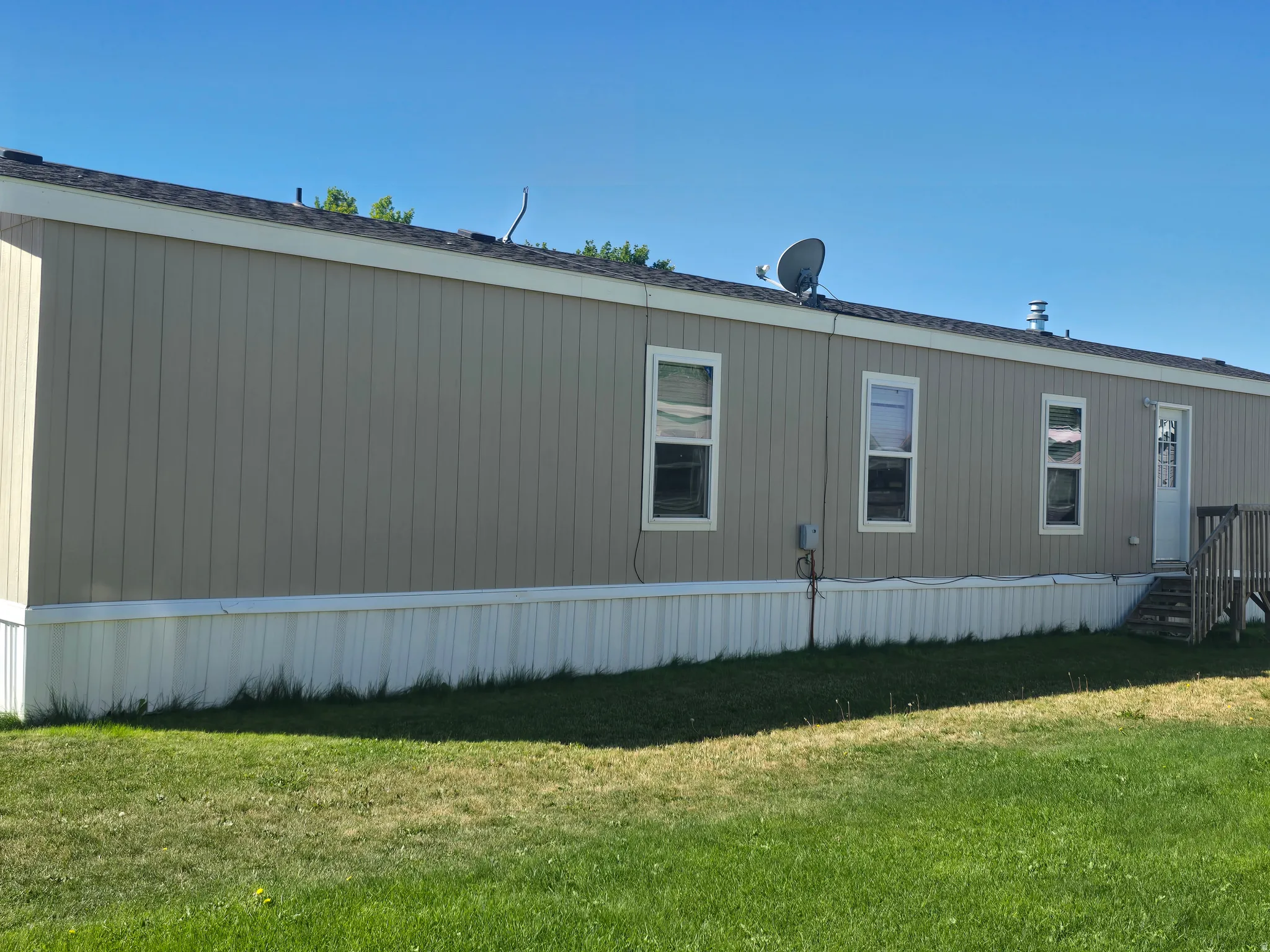 Exterior featuring vertical panel siding, multiple windows, and a wood deck with stairs