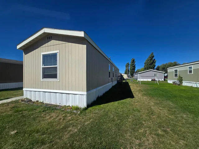 Tan siding exterior with white window trim and a white skirt