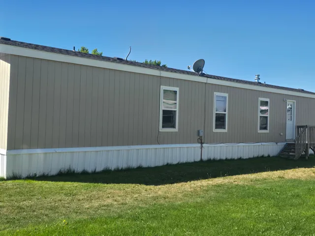 Exterior featuring vertical panel siding, multiple windows, and a wood deck with stairs