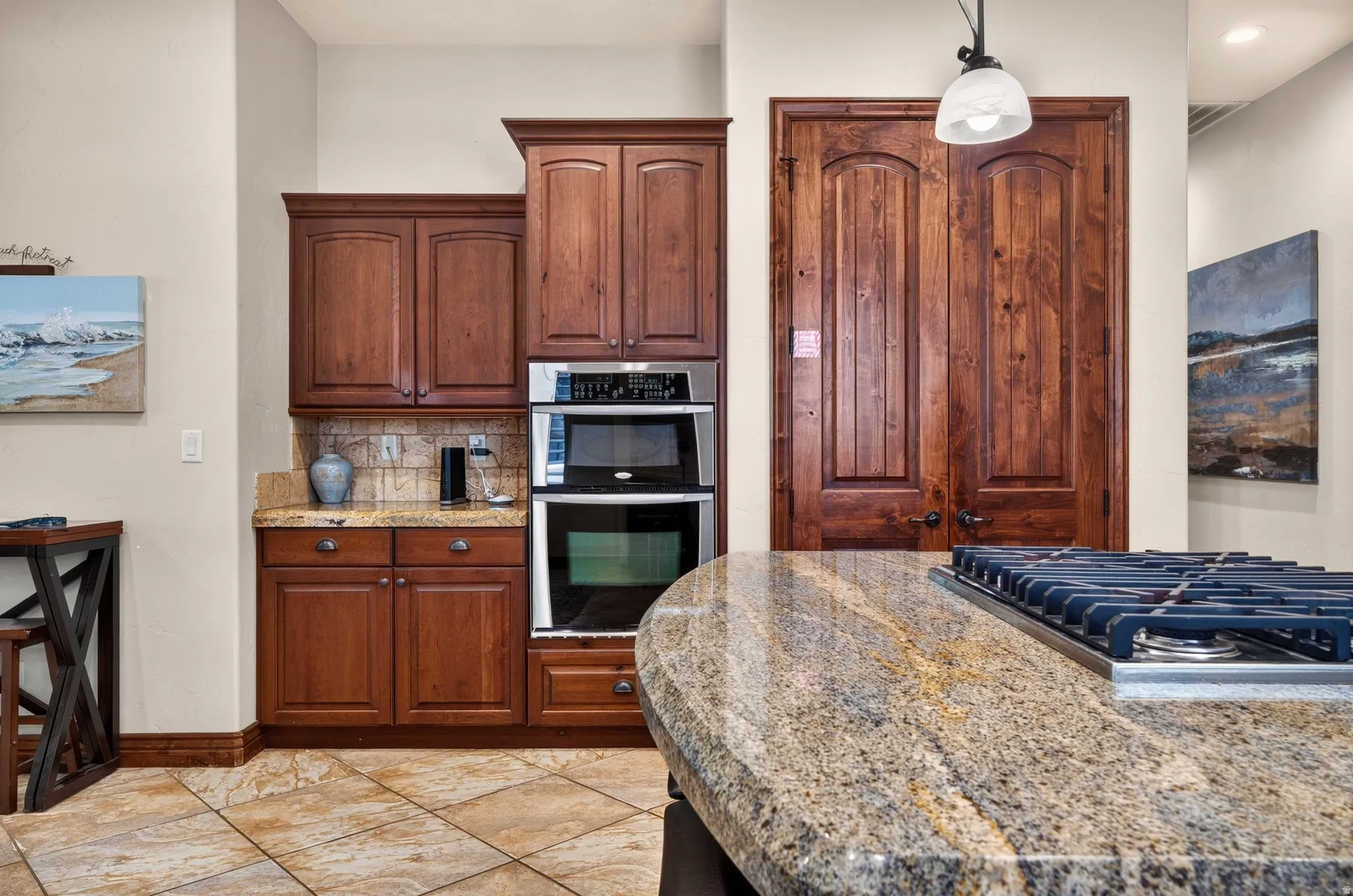 Built-in double oven, wood cabinetry, granite countertops, tile flooring, and a gas cooktop