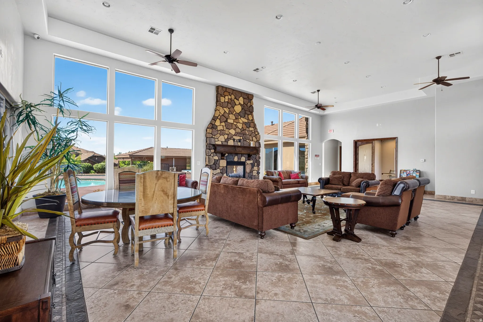 Vaulted ceilings, large stone fireplace, extensive tile flooring, large windows, and recessed lighting