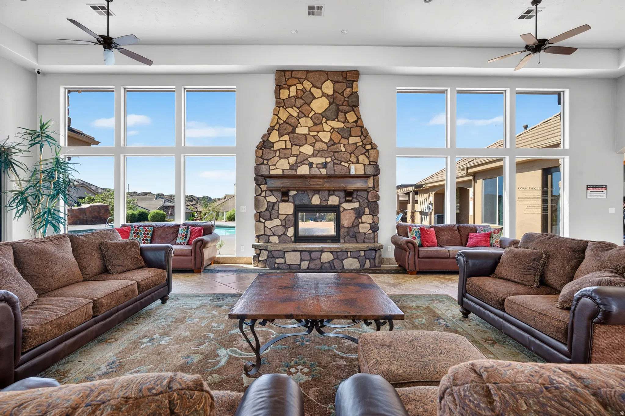 Great room featuring a floor-to-ceiling stone fireplace with a wood mantel, high ceilings, and large picture windows