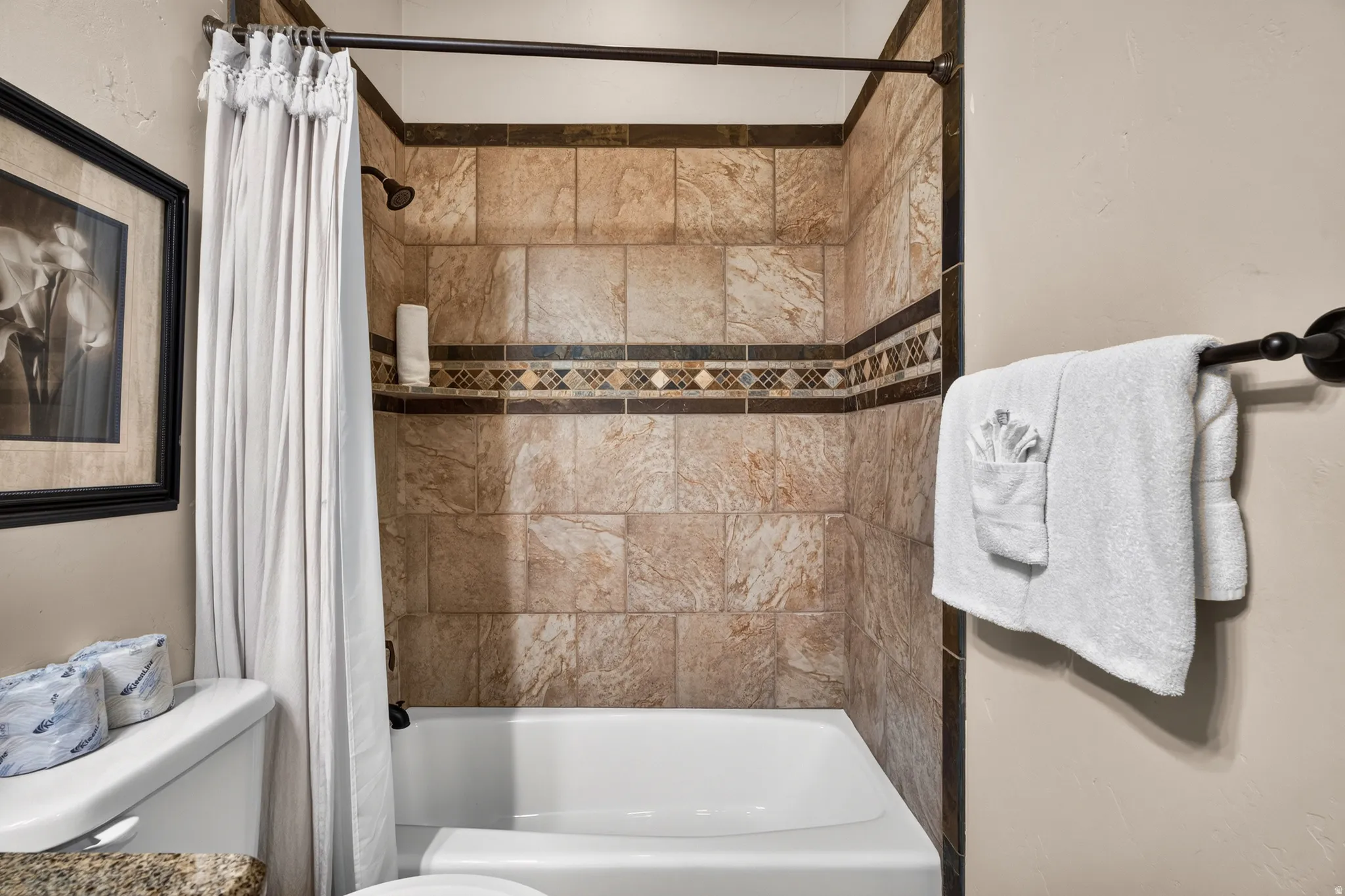 Bathtub with tile surround, decorative tile accent band, and an oil-rubbed bronze showerhead