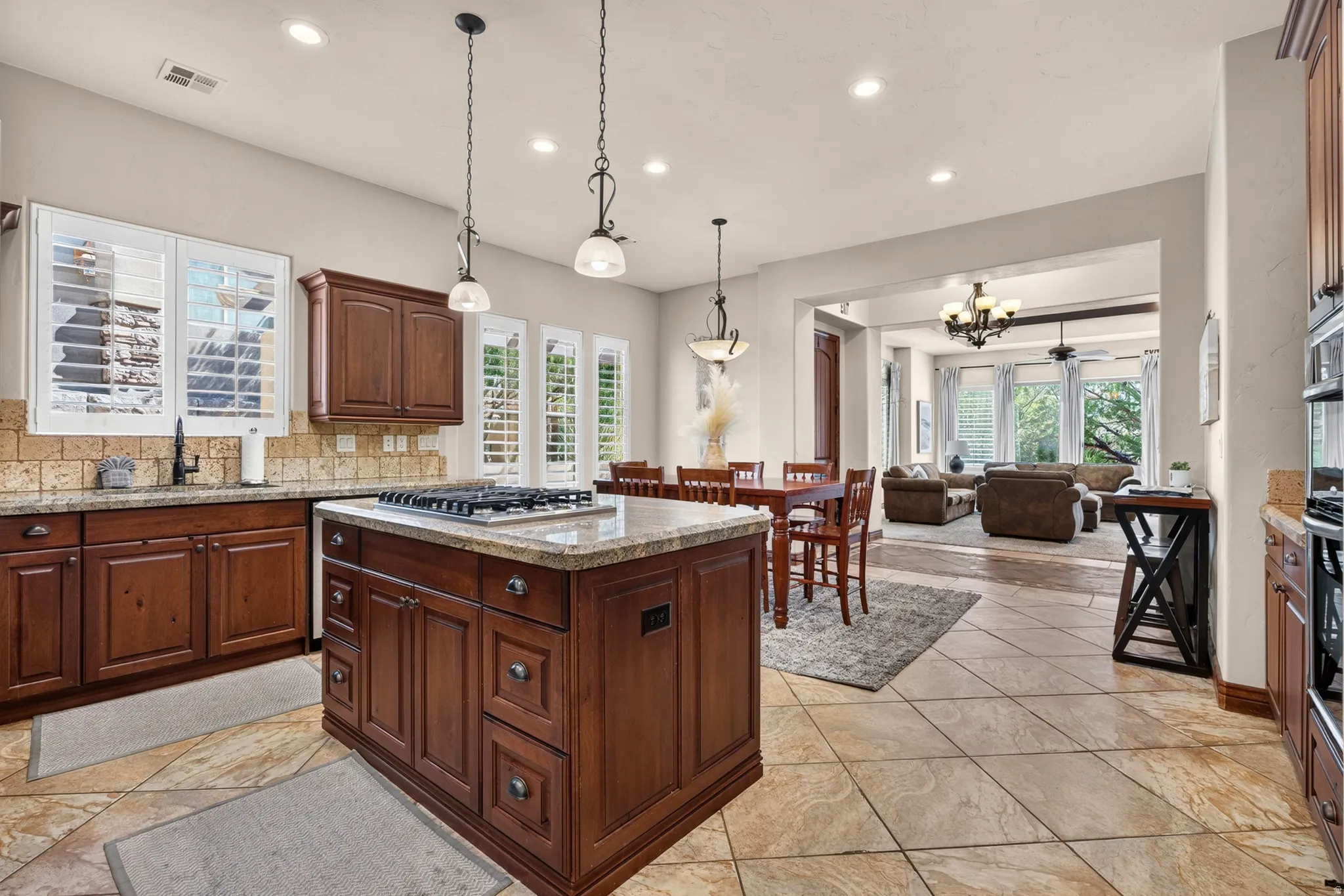 Kitchen featuring an island with a built-in gas cooktop, rich wood cabinetry, stone countertops, and tile flooring