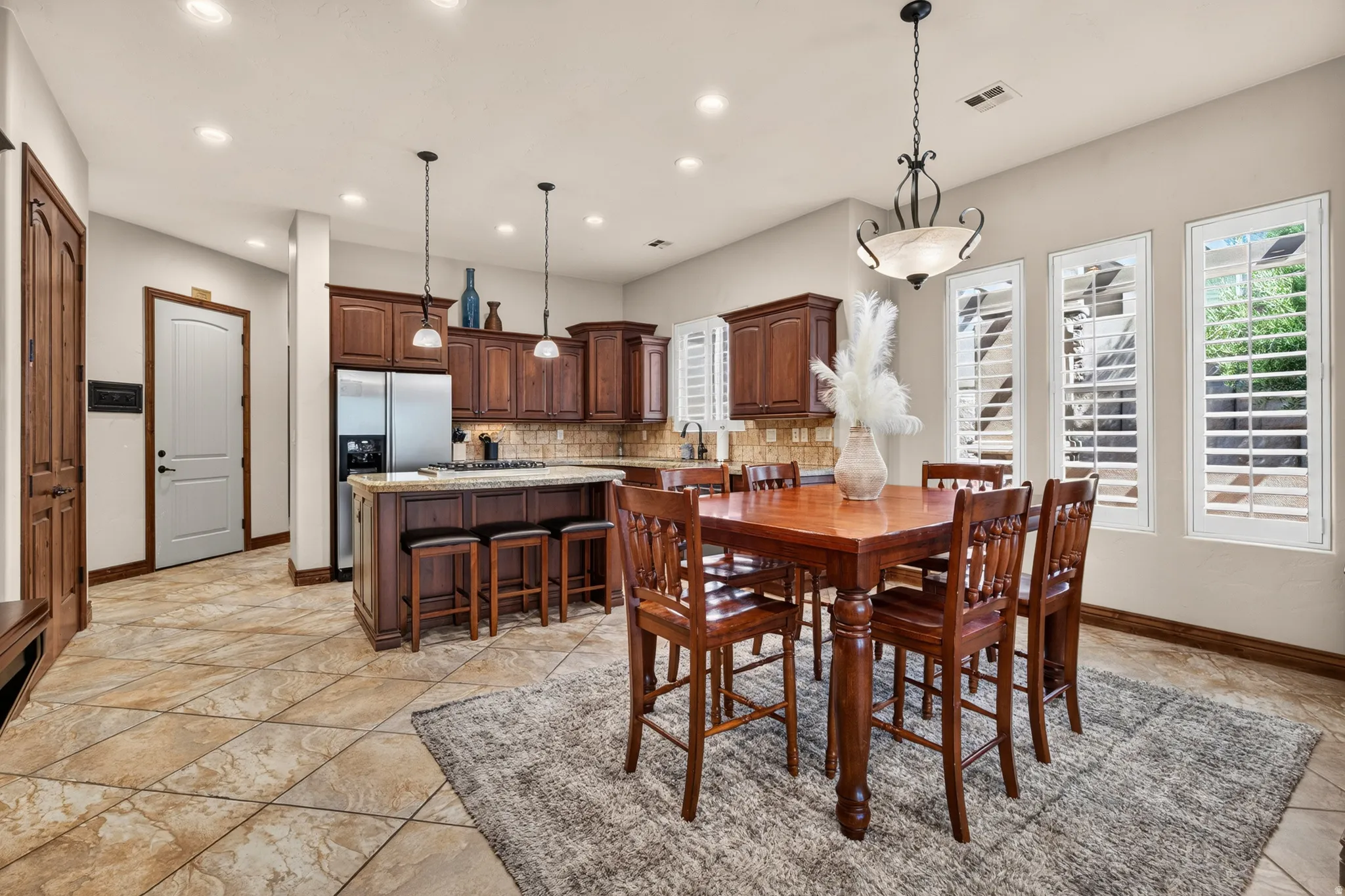 Kitchen featuring wood cabinetry, stainless steel appliances, a center island with bar seating, and a tile backsplash