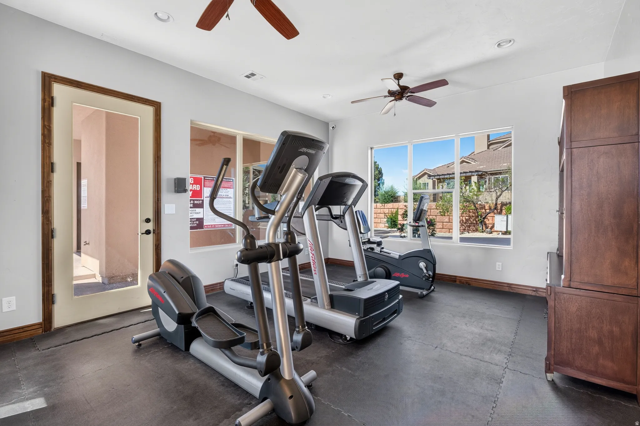 Interior space featuring rubber mat flooring, ceiling fans, and large windows