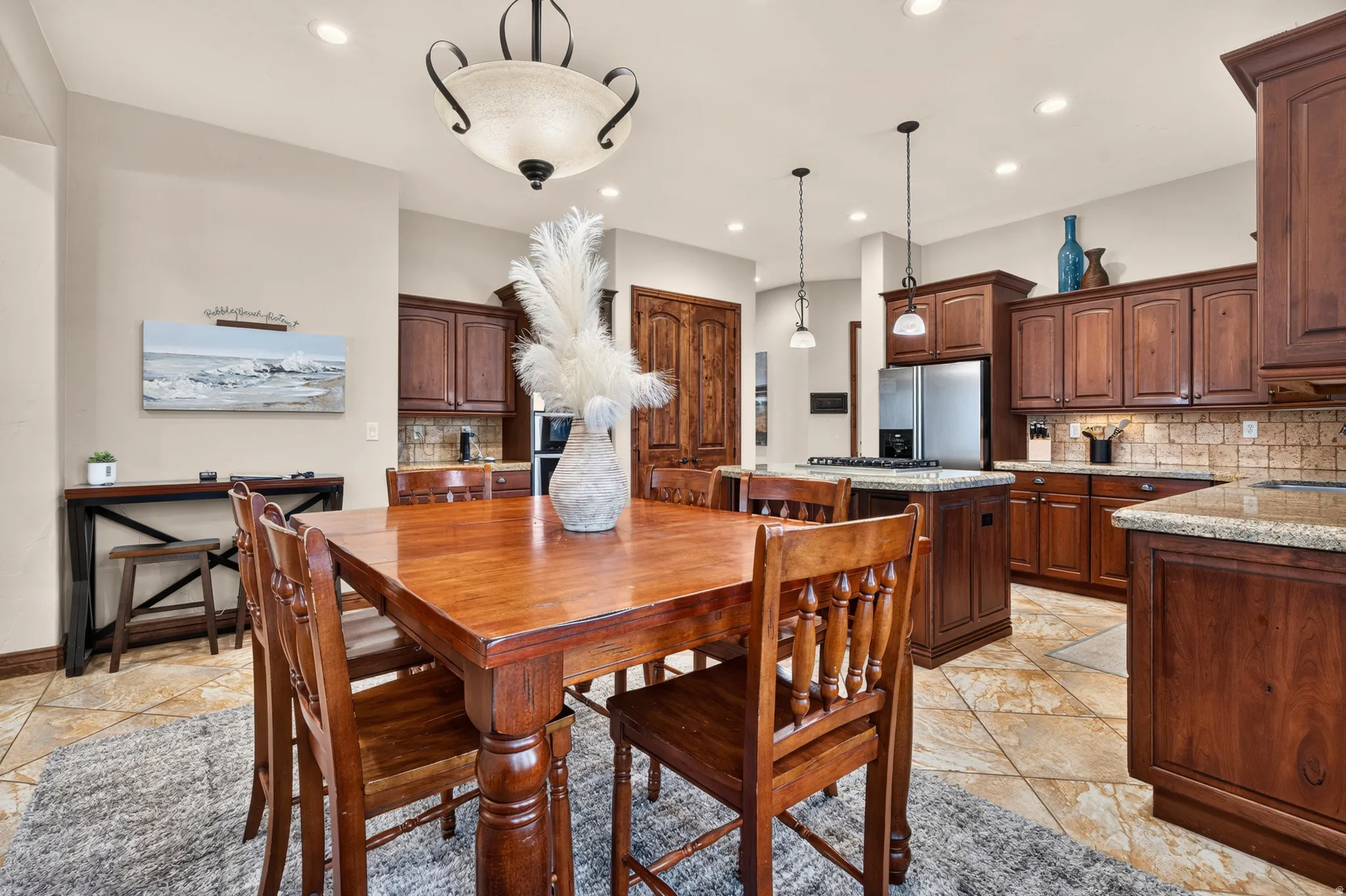 Kitchen and dining area featuring stone tile flooring, stained wood cabinetry, and recessed lighting
