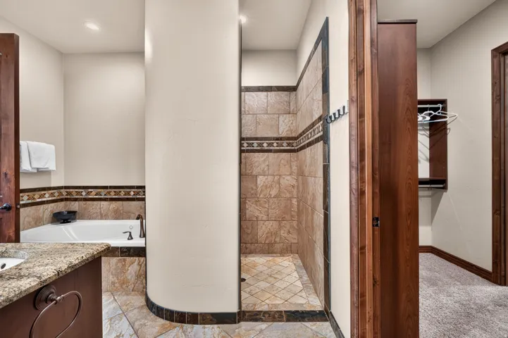 Walk-in shower with tiled walls and floor, adjacent to a built-in bathtub with tiled surround