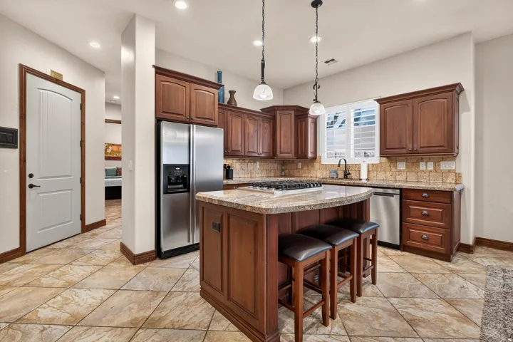 Kitchen featuring a central island with a granite countertop, gas cooktop, and pendant lighting