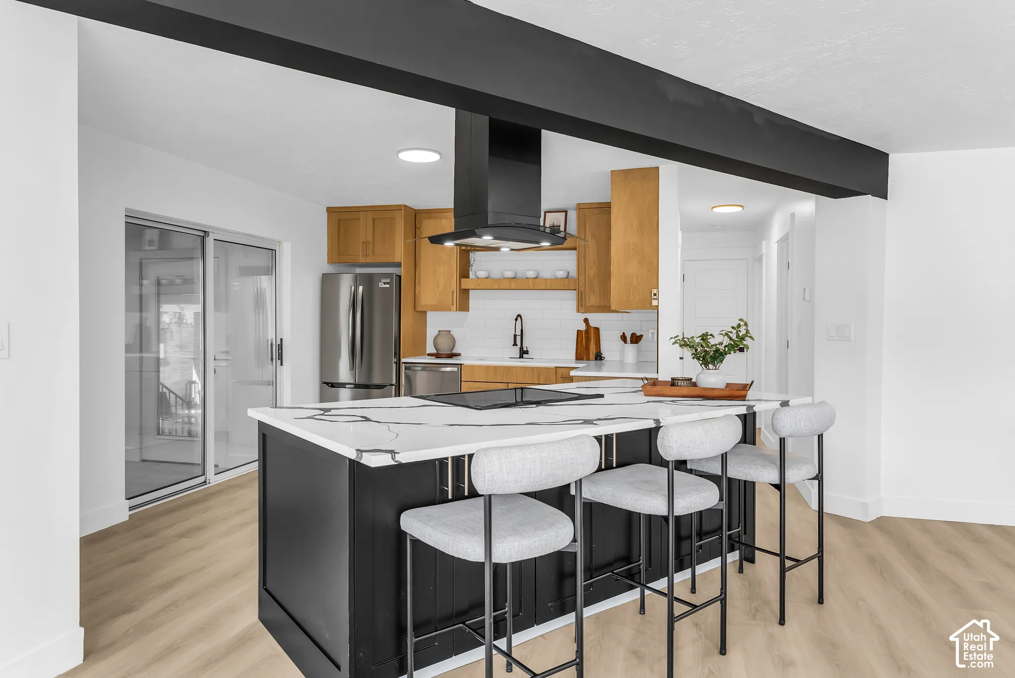 Kitchen island with a light-toned countertop, integrated cooktop, and black cabinetry